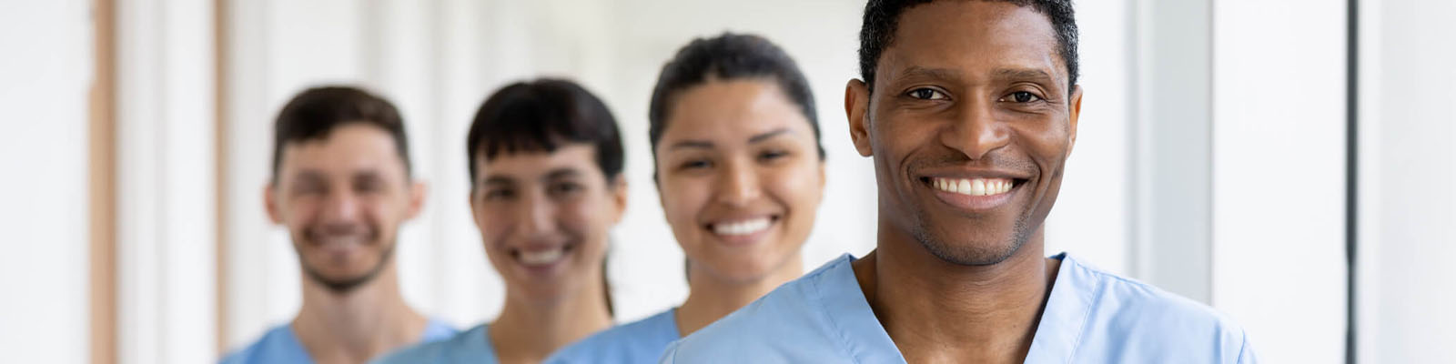 A group of male and female senior living nursing assistant standing in a staggered line behind each other while smiling