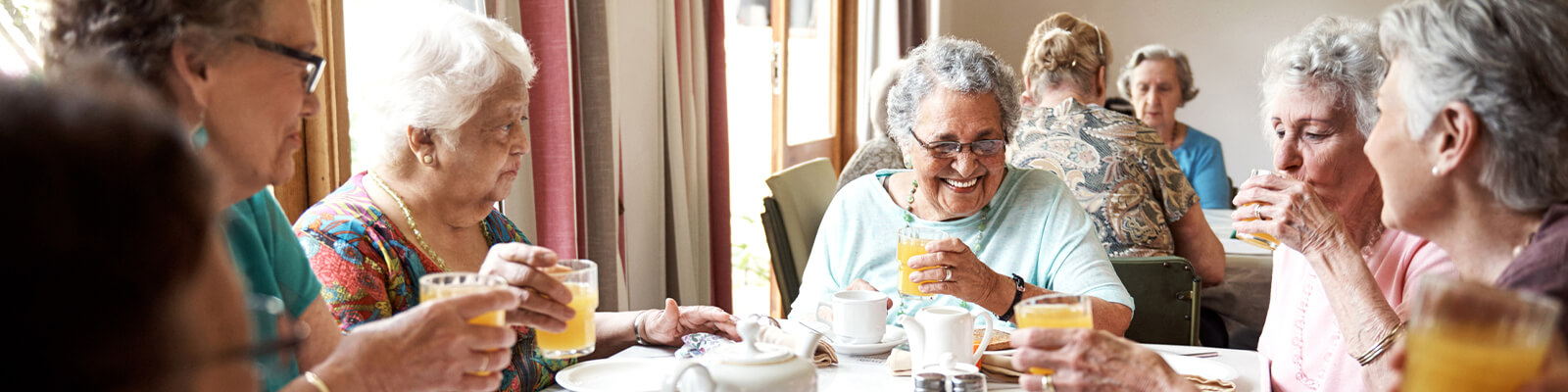 A group of senior living residents sitting at a table in a dining area in a senior living facility for breakfast