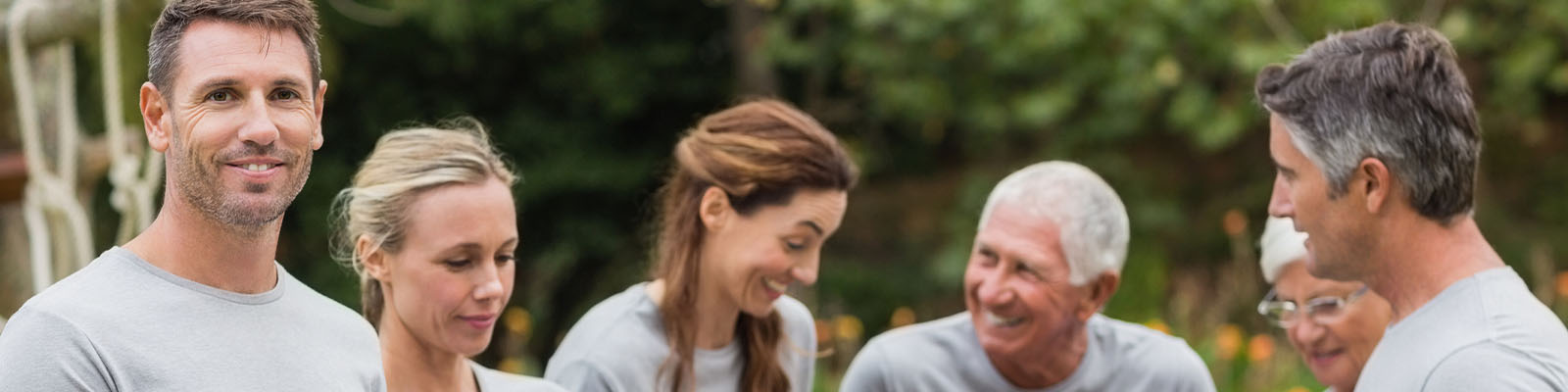 A group of men and women volunteering outdoors at a senior living facility
